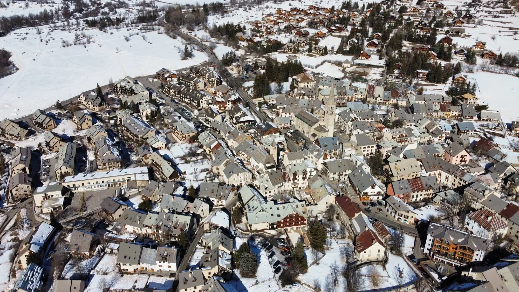 Aerial view of the snowy rooftops of Le Monêtier-les-Bains village in February.