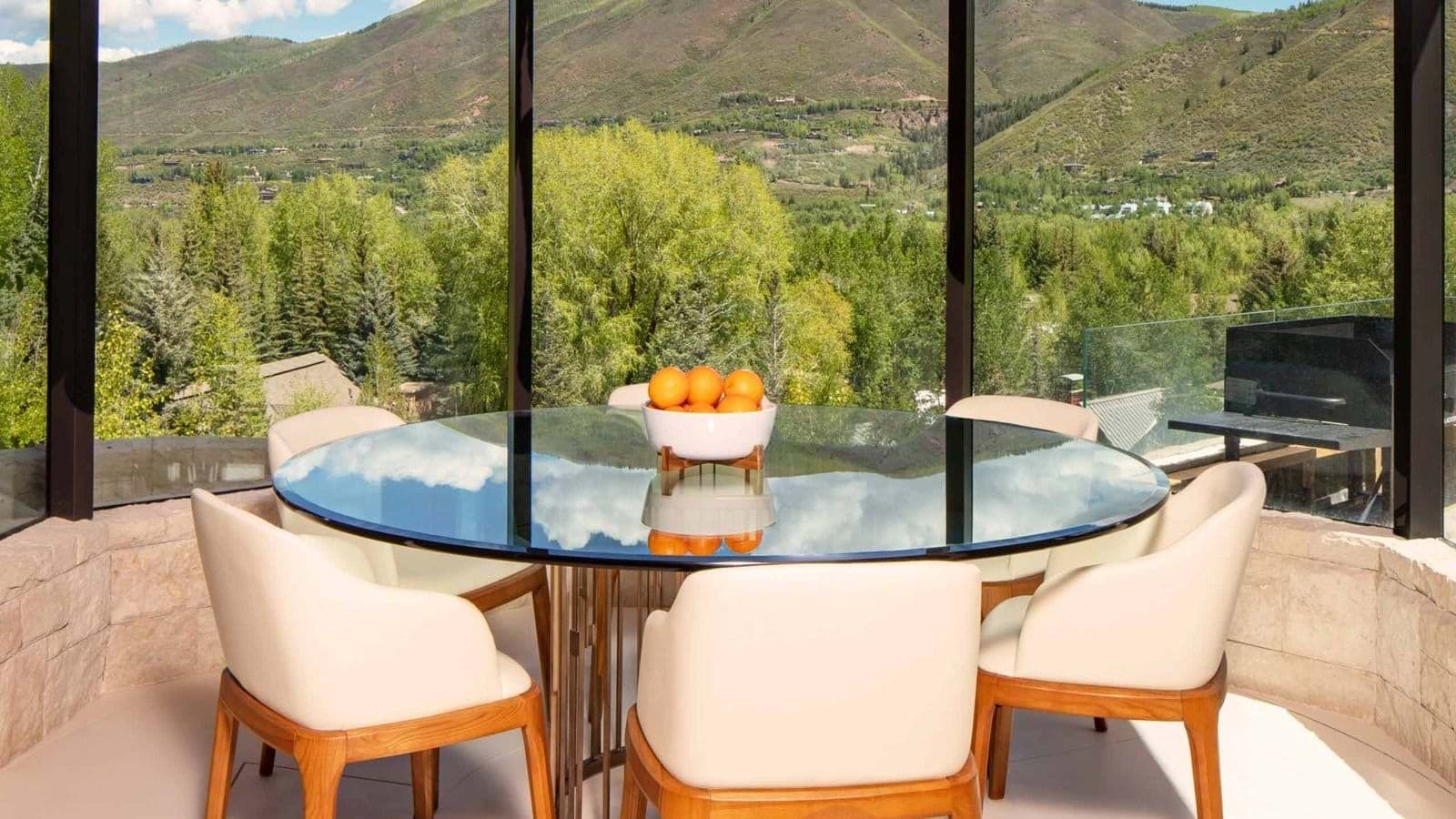 Round glass dining table seats 6 with mountain valley views