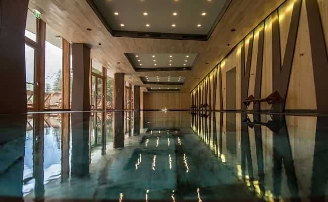 Indoor lap pool with wood-paneled walls and mountain views