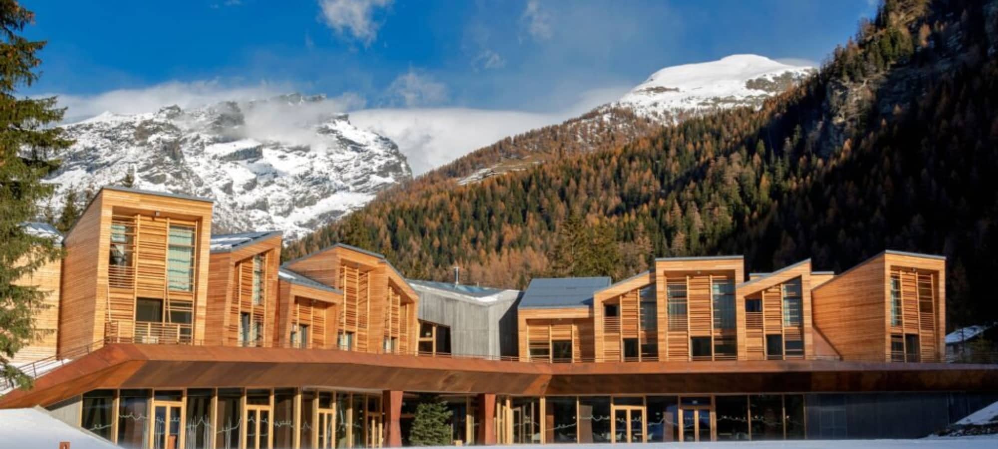 Timber-clad exterior with private balconies and snow-capped mountain backdrop