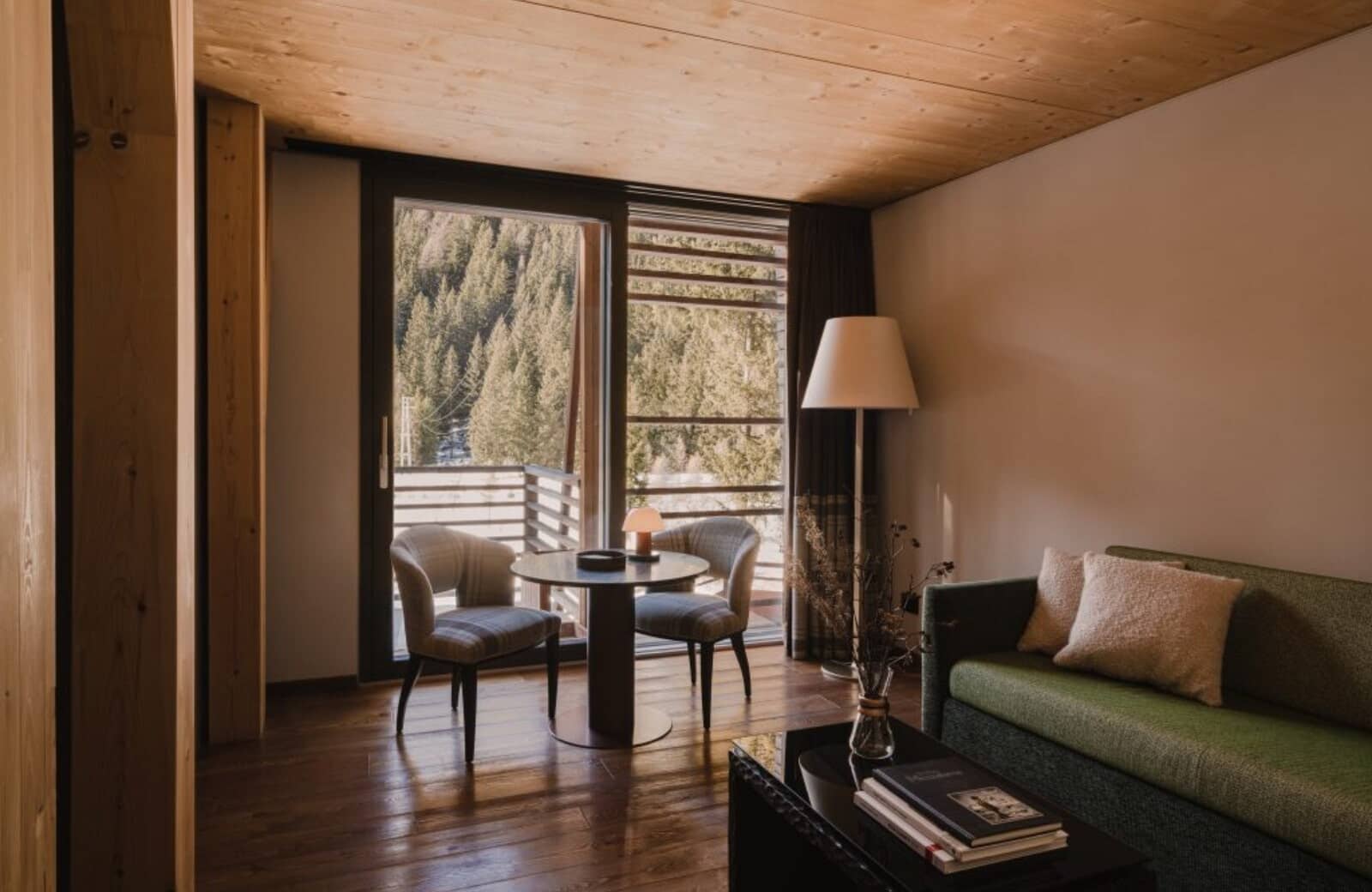 Living area with sofa bed and forest views through floor-to-ceiling windows