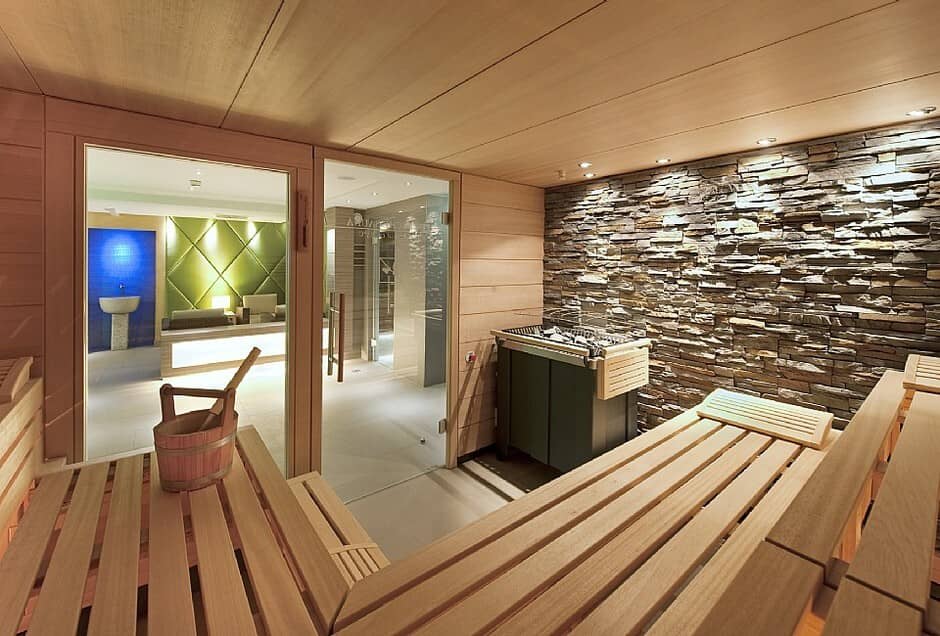 Private sauna with tiered cedar seating and stone accent wall
