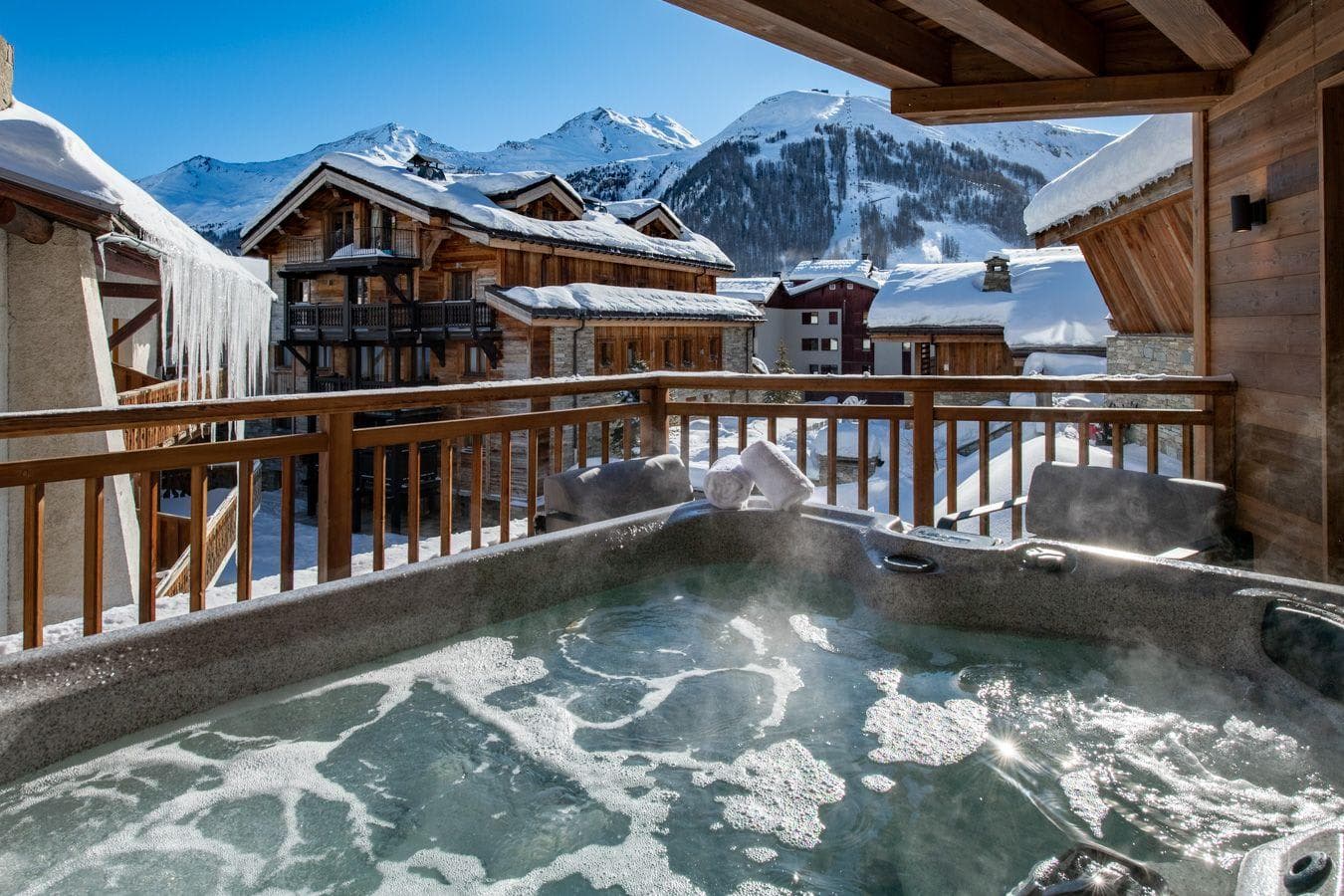 Outdoor hot tub on private balcony with mountain and ski slope views