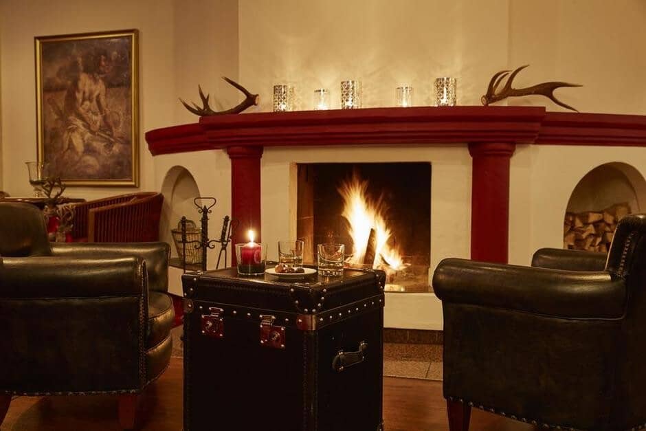 Living room with dual leather chairs, wood-burning fireplace, and antler mantel décor
