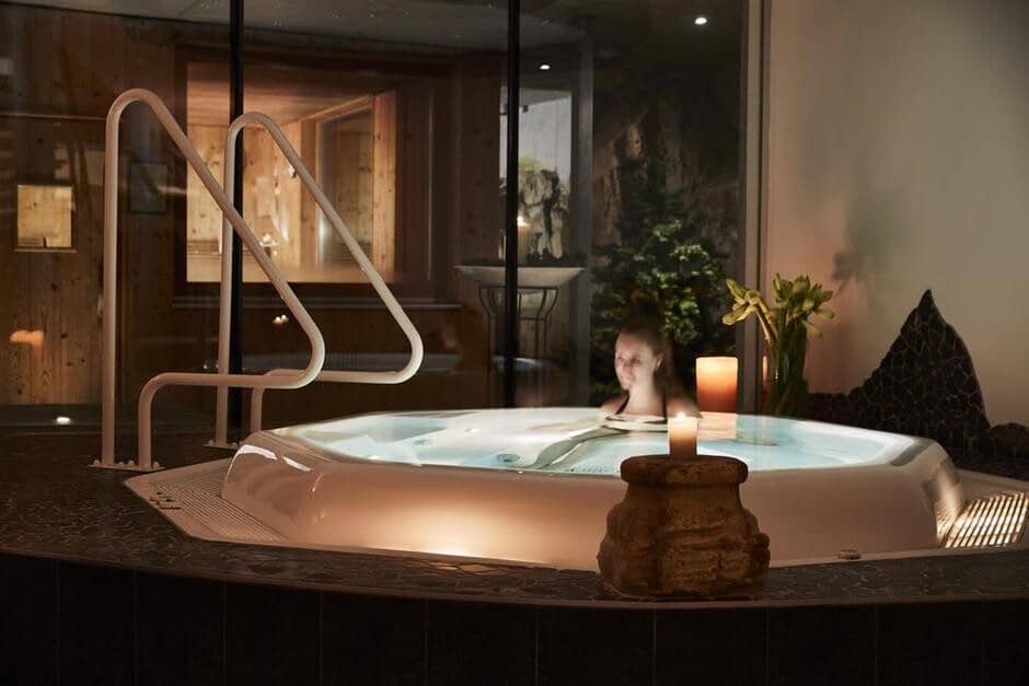 Soaking tub with integrated jets; candle-lit spa ambiance and glass entry doors