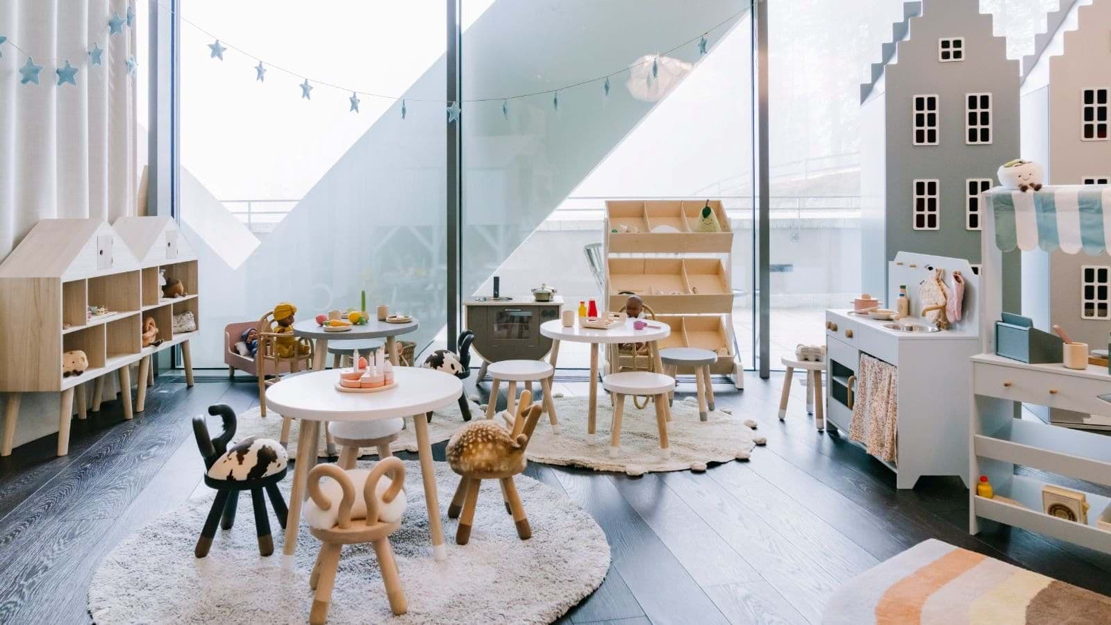 Children's playroom with play kitchen, activity tables, and floor-to-ceiling windows