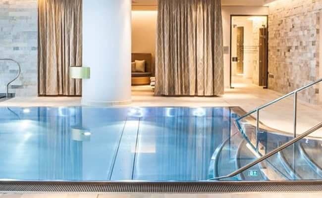 Indoor pool with stainless steel stairs and nearby relaxation lounge