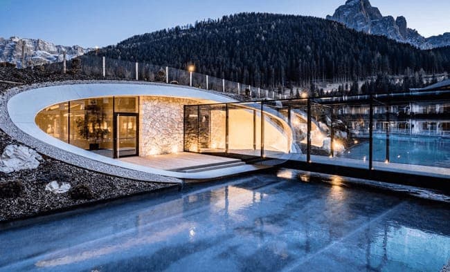 Earth-sheltered building with glass walkway and panoramic mountain views