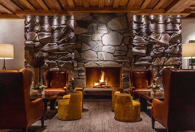 Lounge with floor-to-ceiling stone fireplace and leather wingback seating