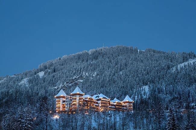 Mountainside resort exterior with illuminated balconies and forested surroundings
