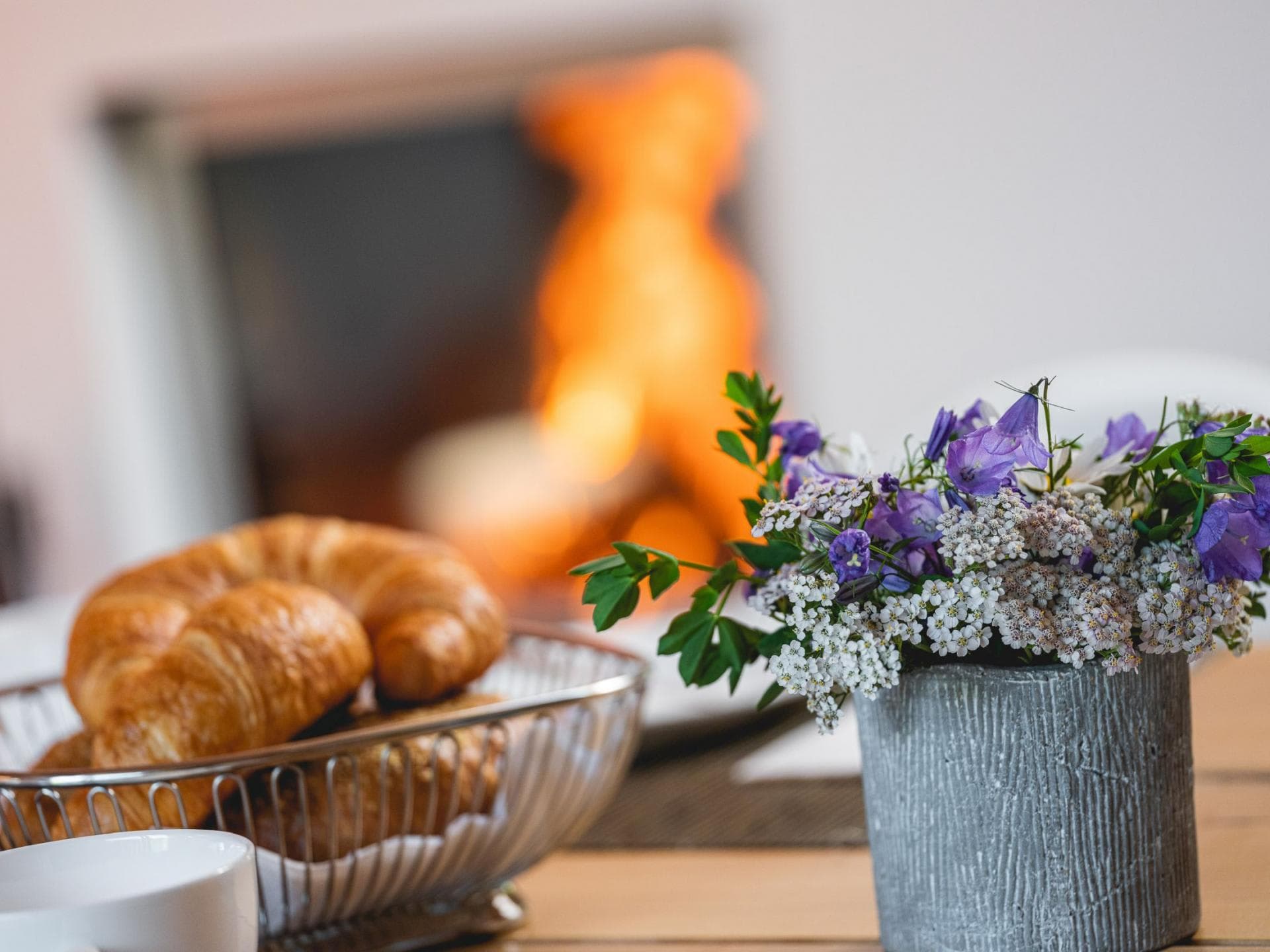 Dining table breakfast setup with wood-burning fireplace in background