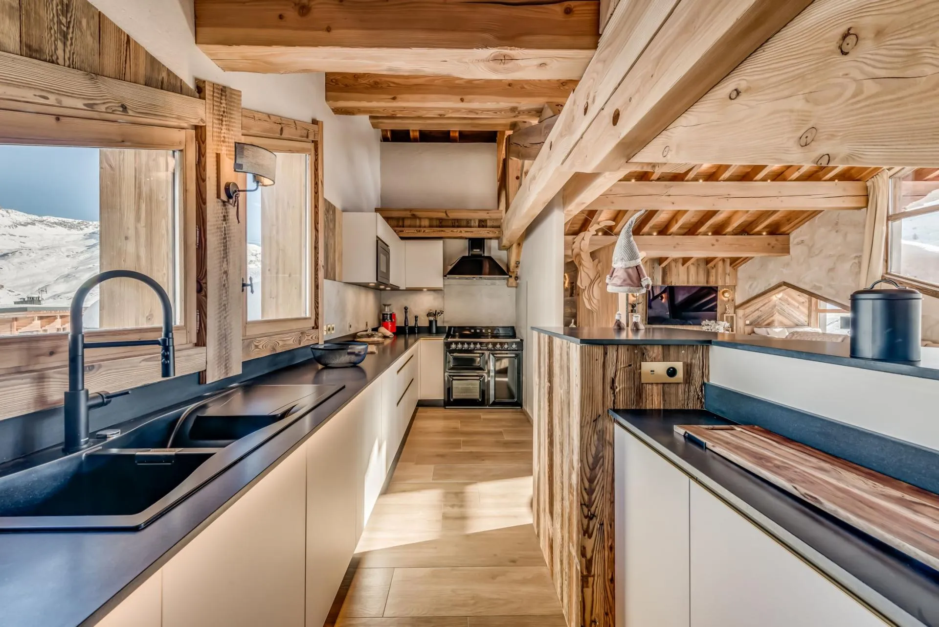 Galley kitchen with Lacanche range, exposed timber beams, and mountain views