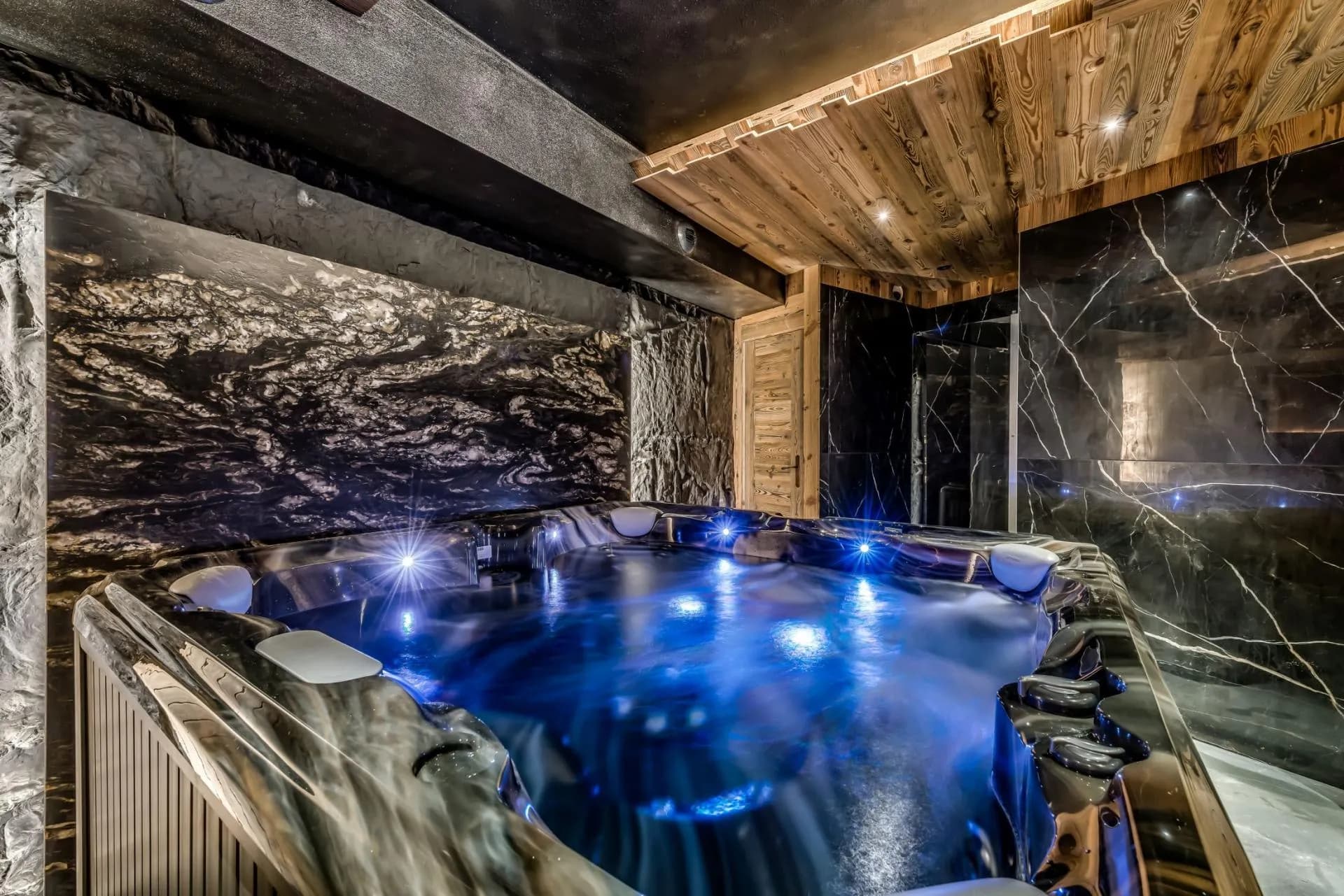 Indoor hot tub with LED lighting and marble-tiled spa area