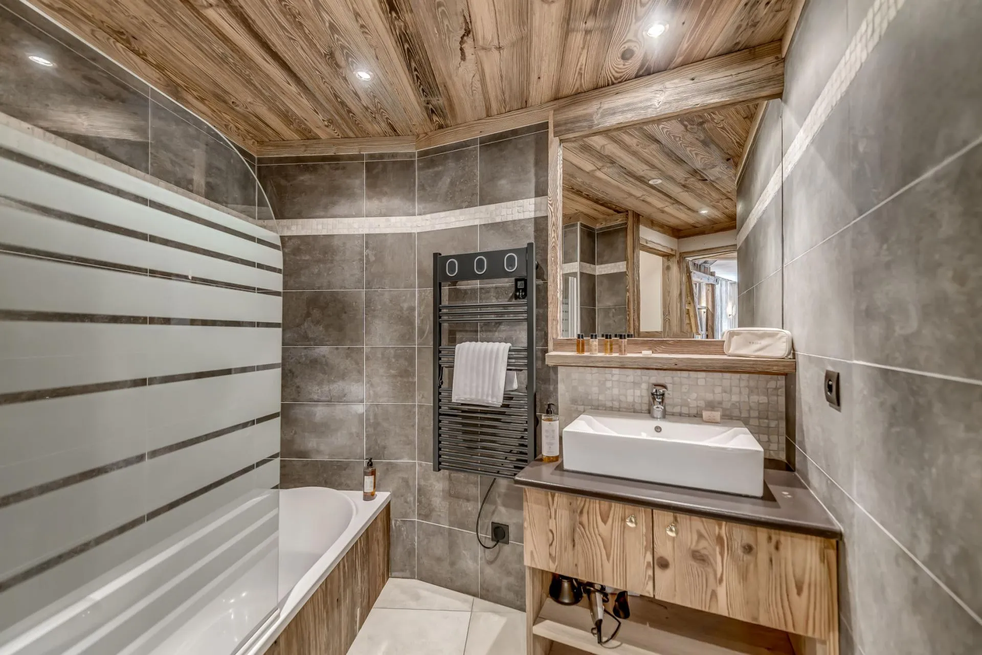 Bathroom with soaking tub, vessel sink, and heated towel rack