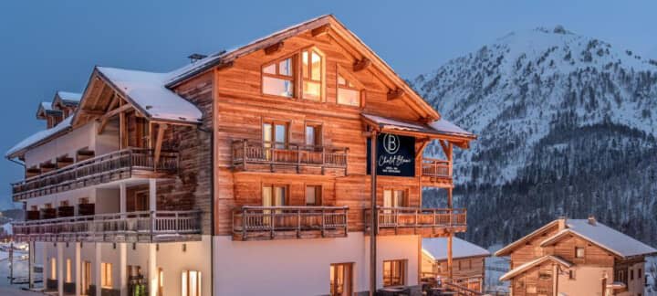 Ski-in chalet exterior with private balconies and mountain peak backdrop