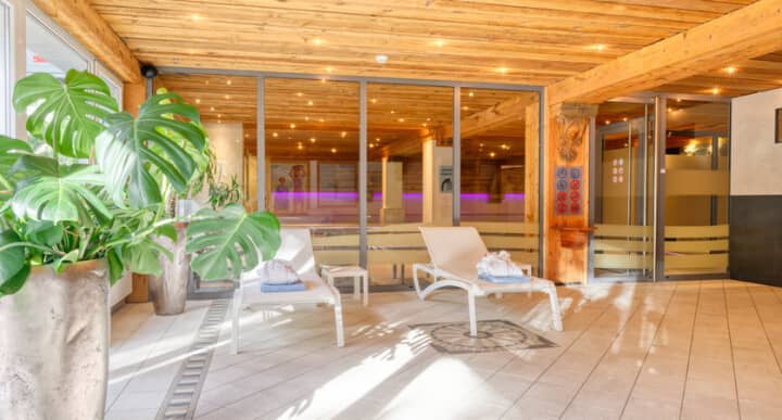 Indoor pool lounge area with reclining chairs and glass partition