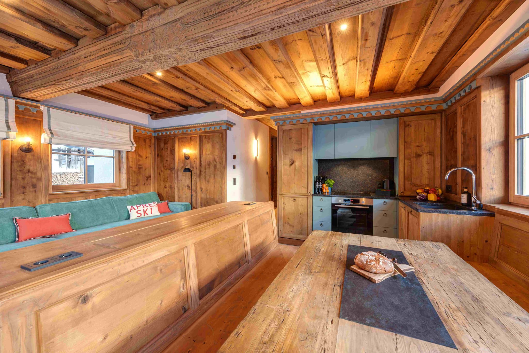 Open-plan kitchen and living area with carved timber ceilings and induction cooktop