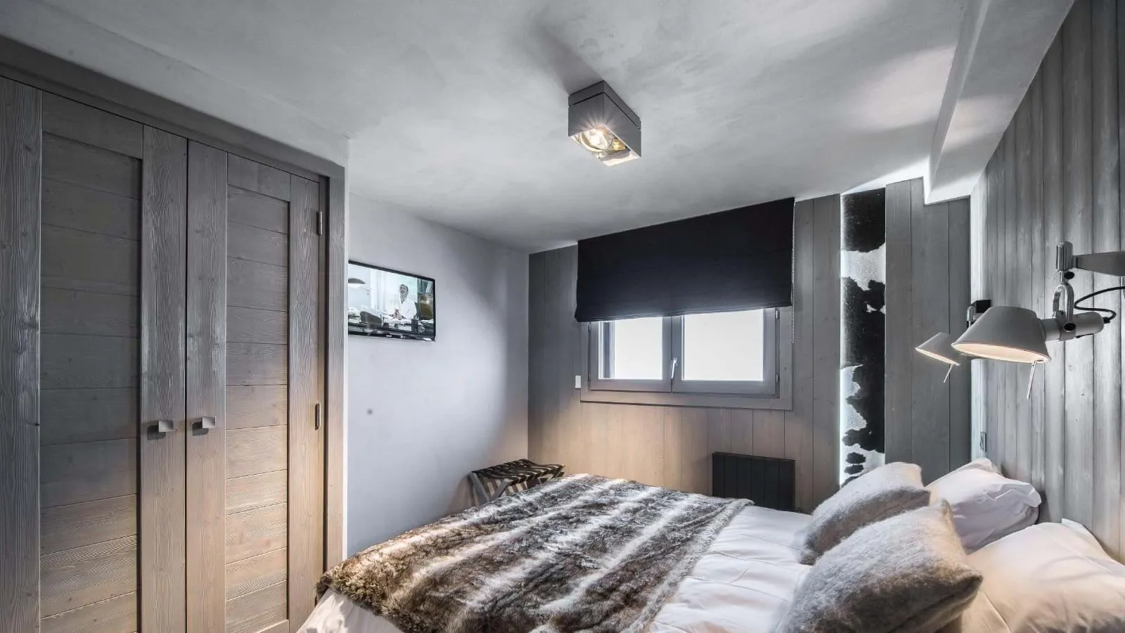 Double bedroom with a wall-mounted television and timber wardrobes