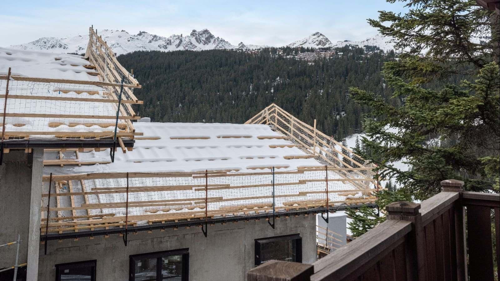 Balcony view of neighboring chalet construction and snow-capped mountain peaks