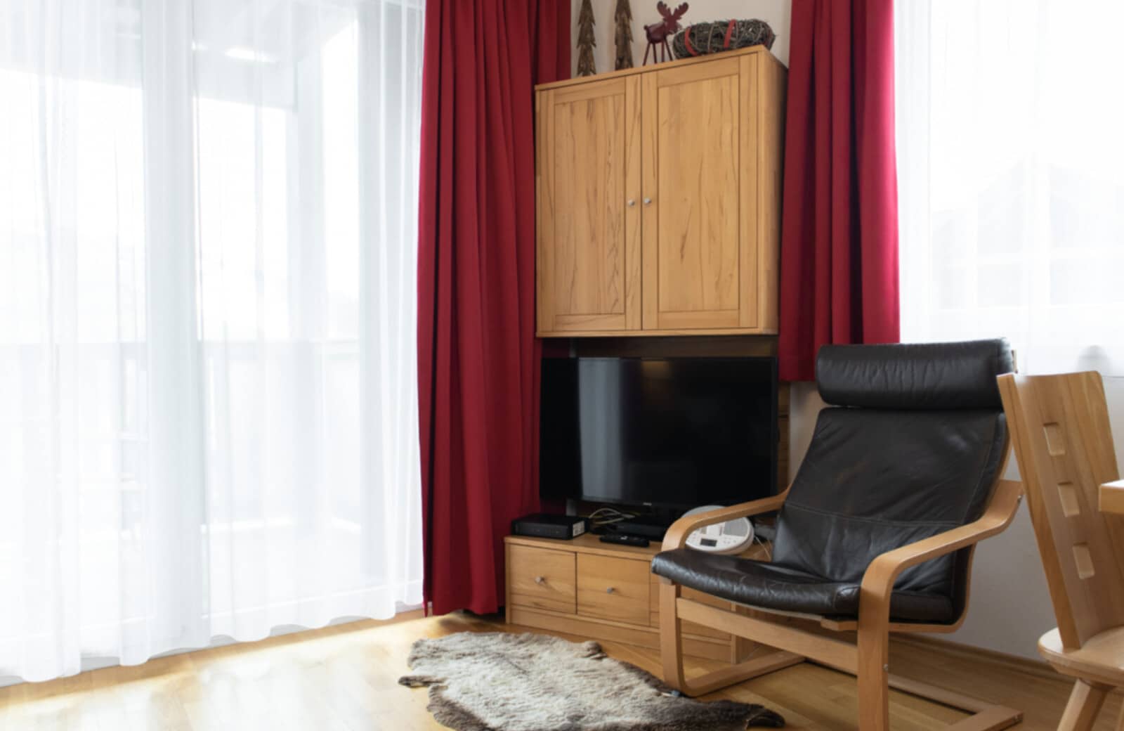 Living area with flat-screen TV and leather armchair near balcony access
