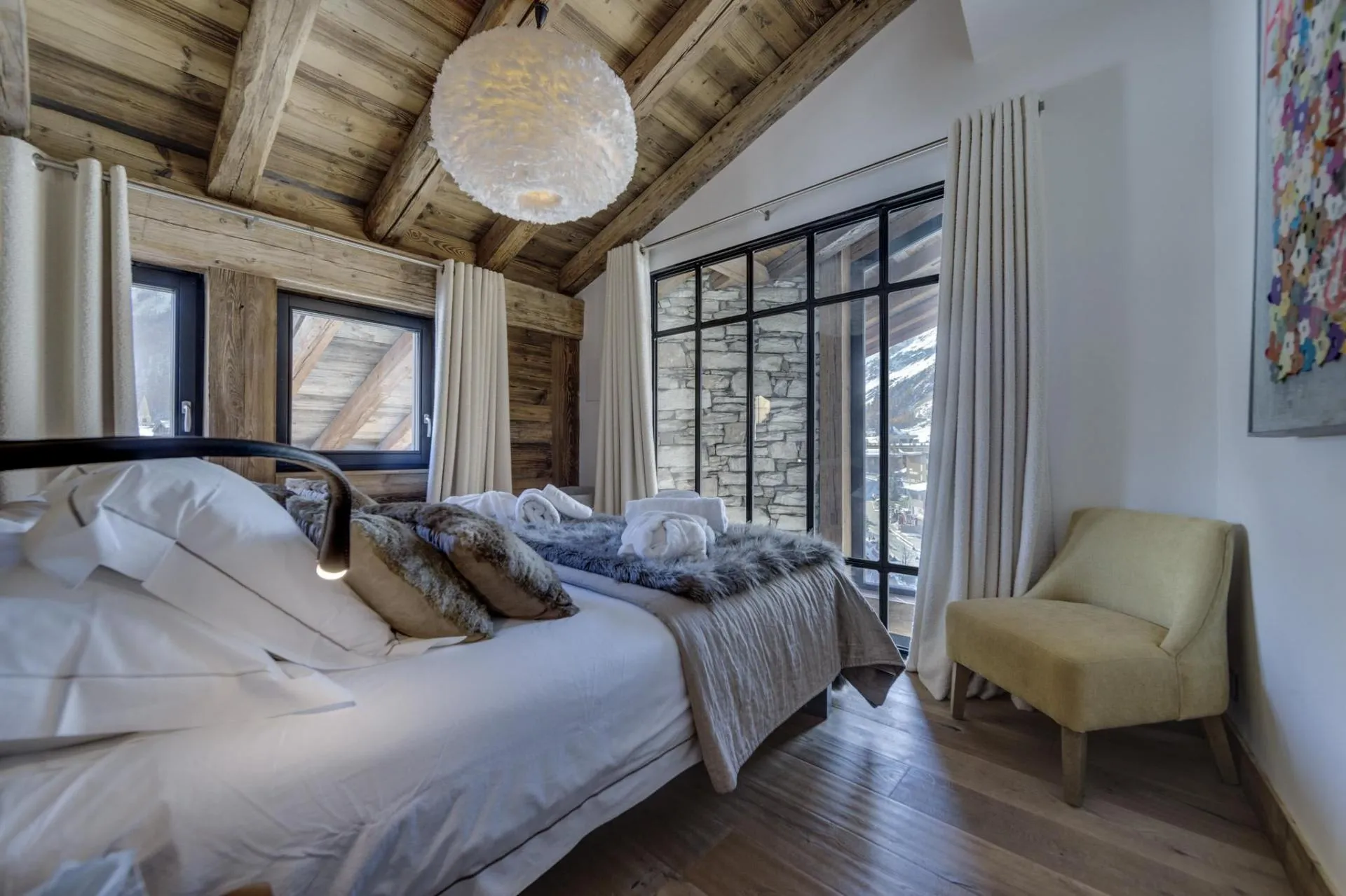 Bedroom with vaulted wood ceilings and black-framed mountain view windows