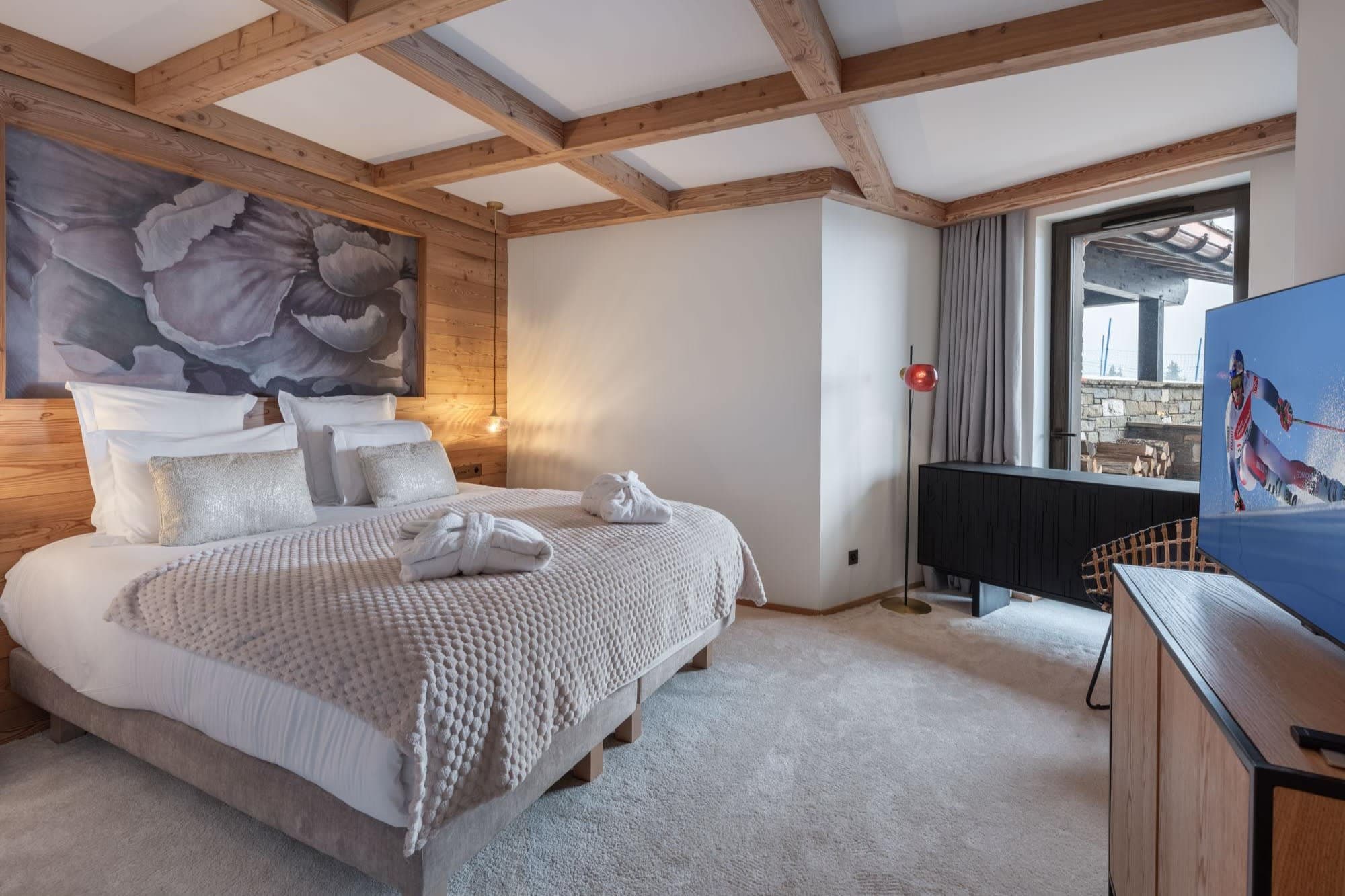 Primary bedroom with king bed, timber-beam ceiling, and terrace access