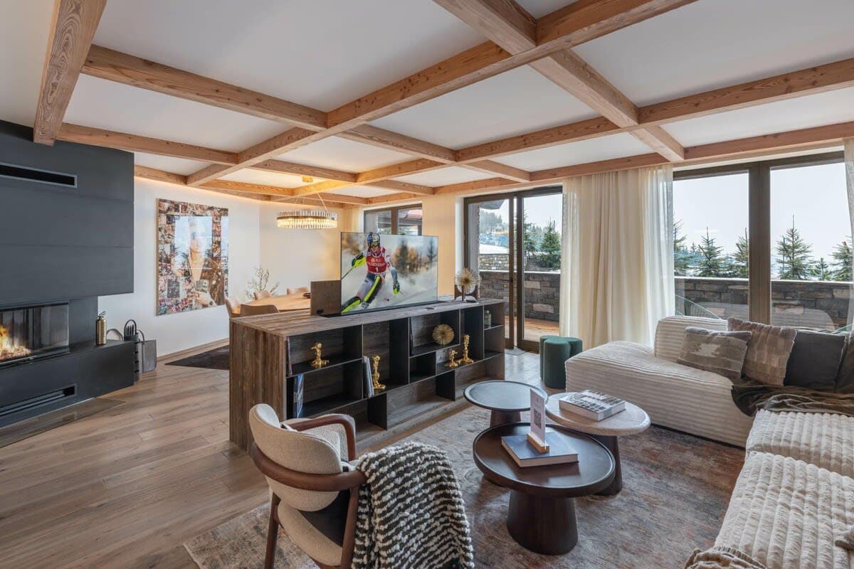Living area with wood-beam ceiling, wood-burning fireplace, and mountain-view balcony