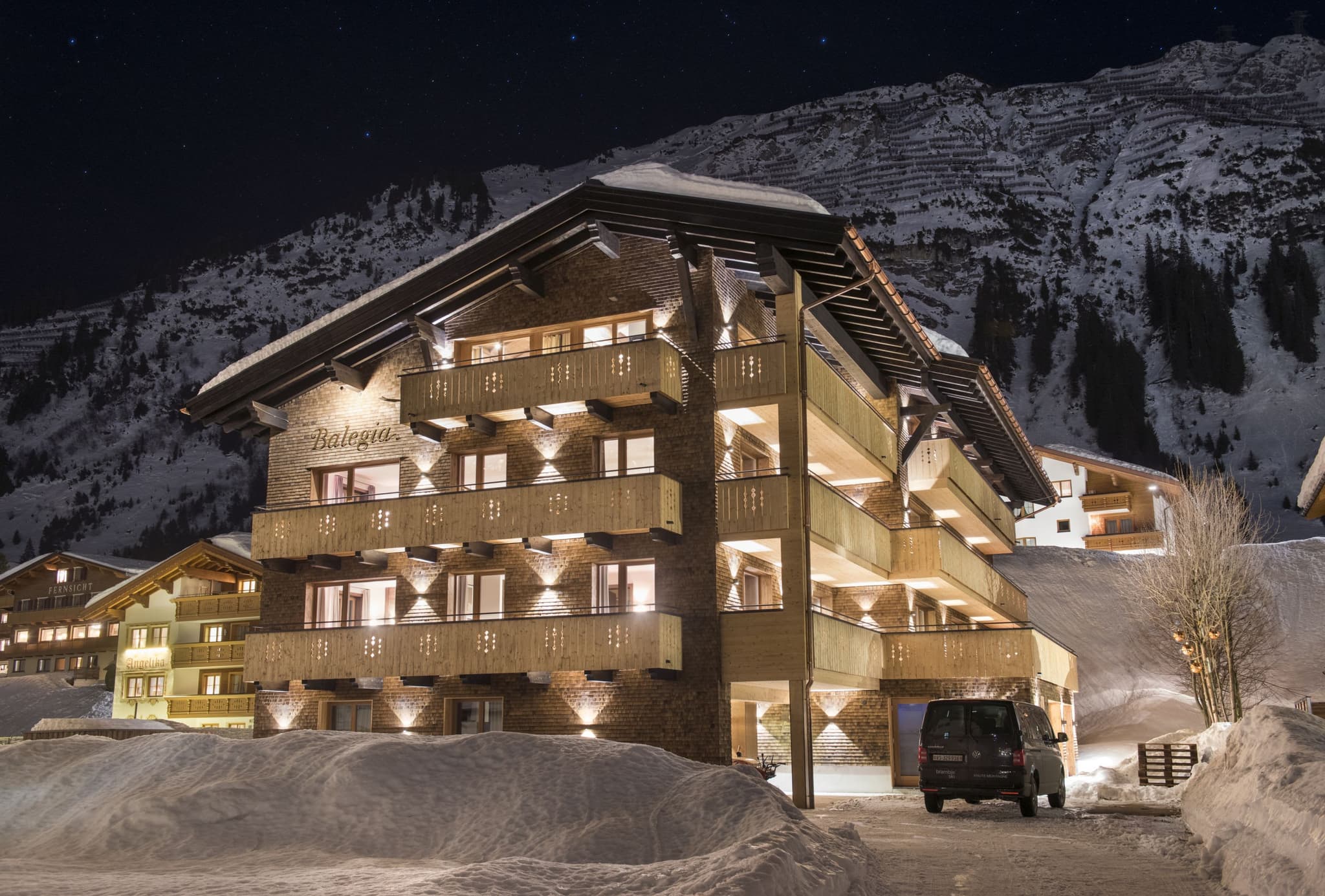 Chalet exterior at night with wrap-around balconies and mountain views