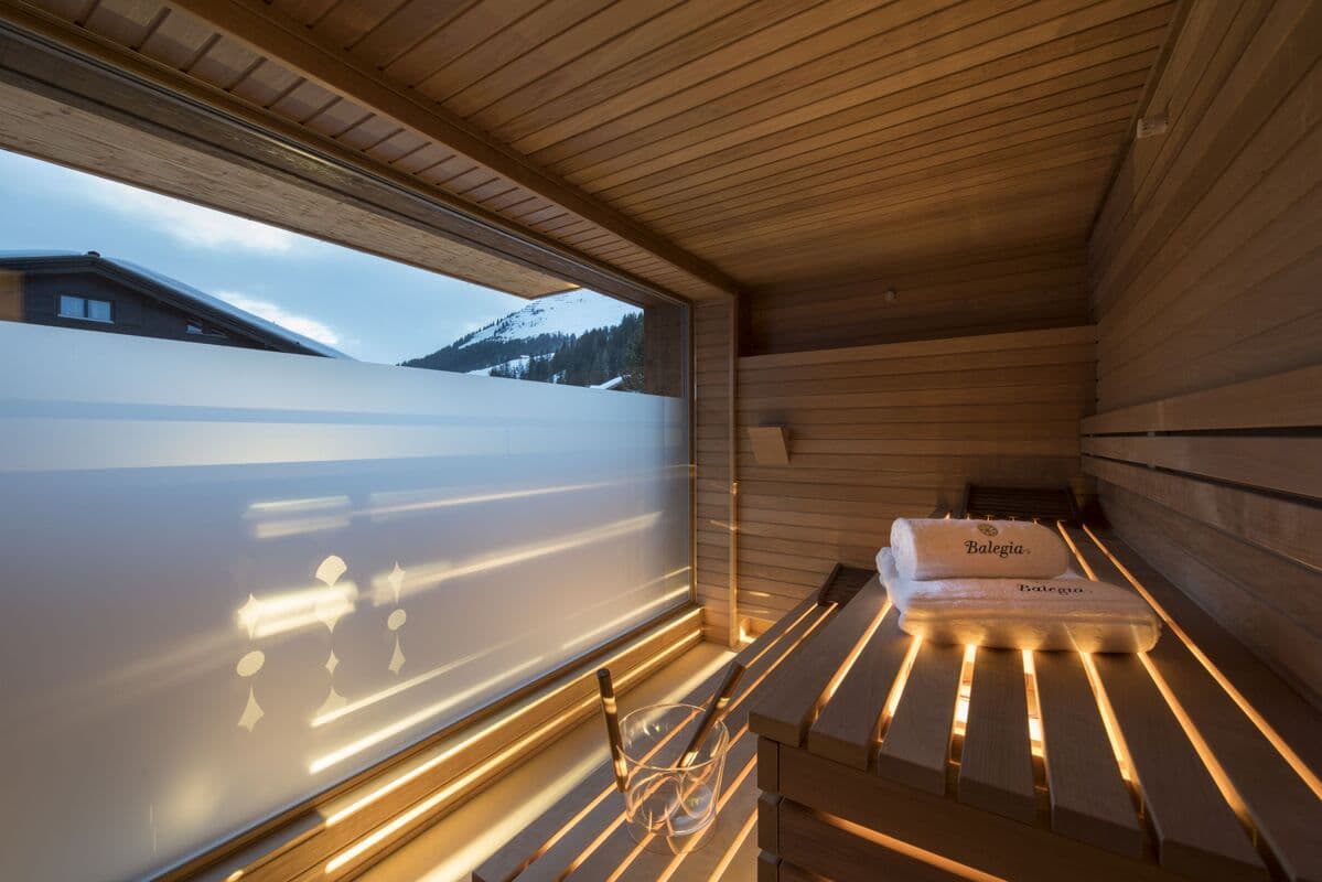 Private sauna with tiered wood seating and frosted mountain-view window