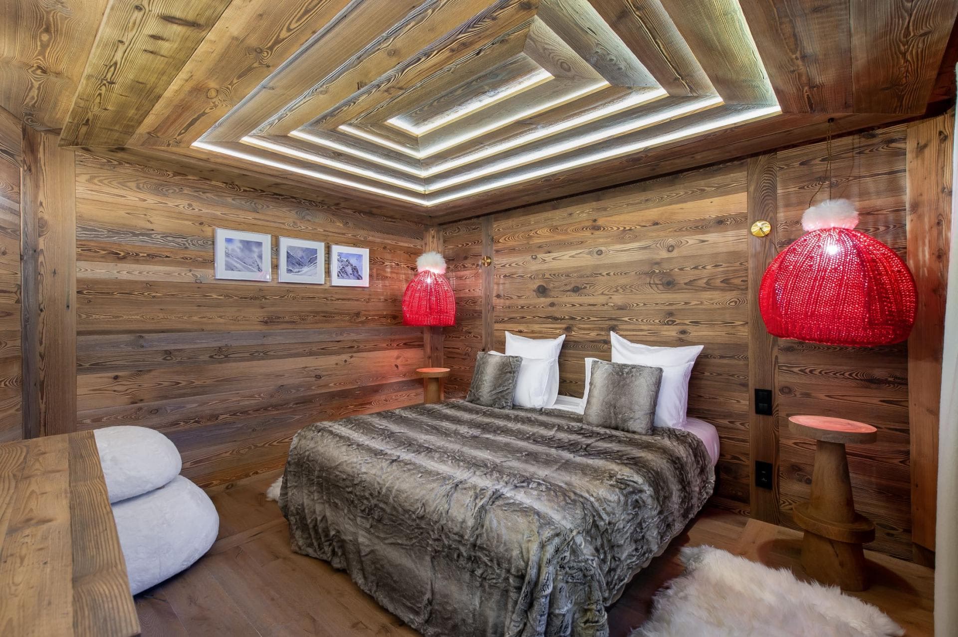 Wood-paneled bedroom with king bed and tiered tray ceiling lighting