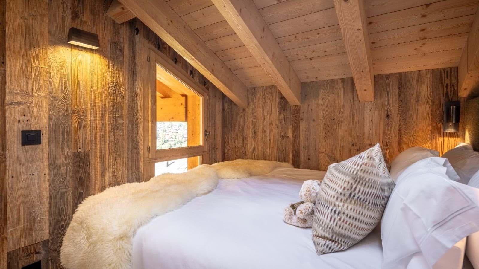Bedroom with sloped wood ceiling and mountain village views