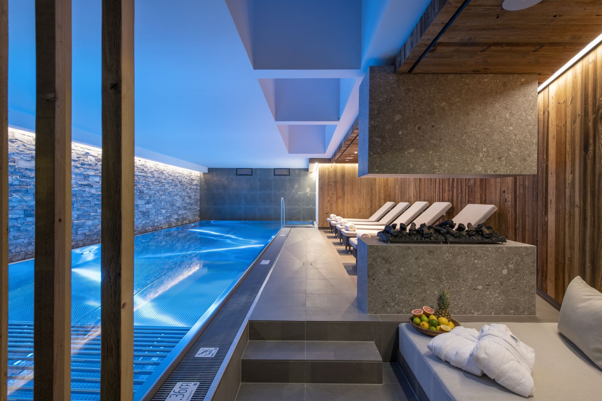 Indoor pool and spa area with loungers and gas fireplace