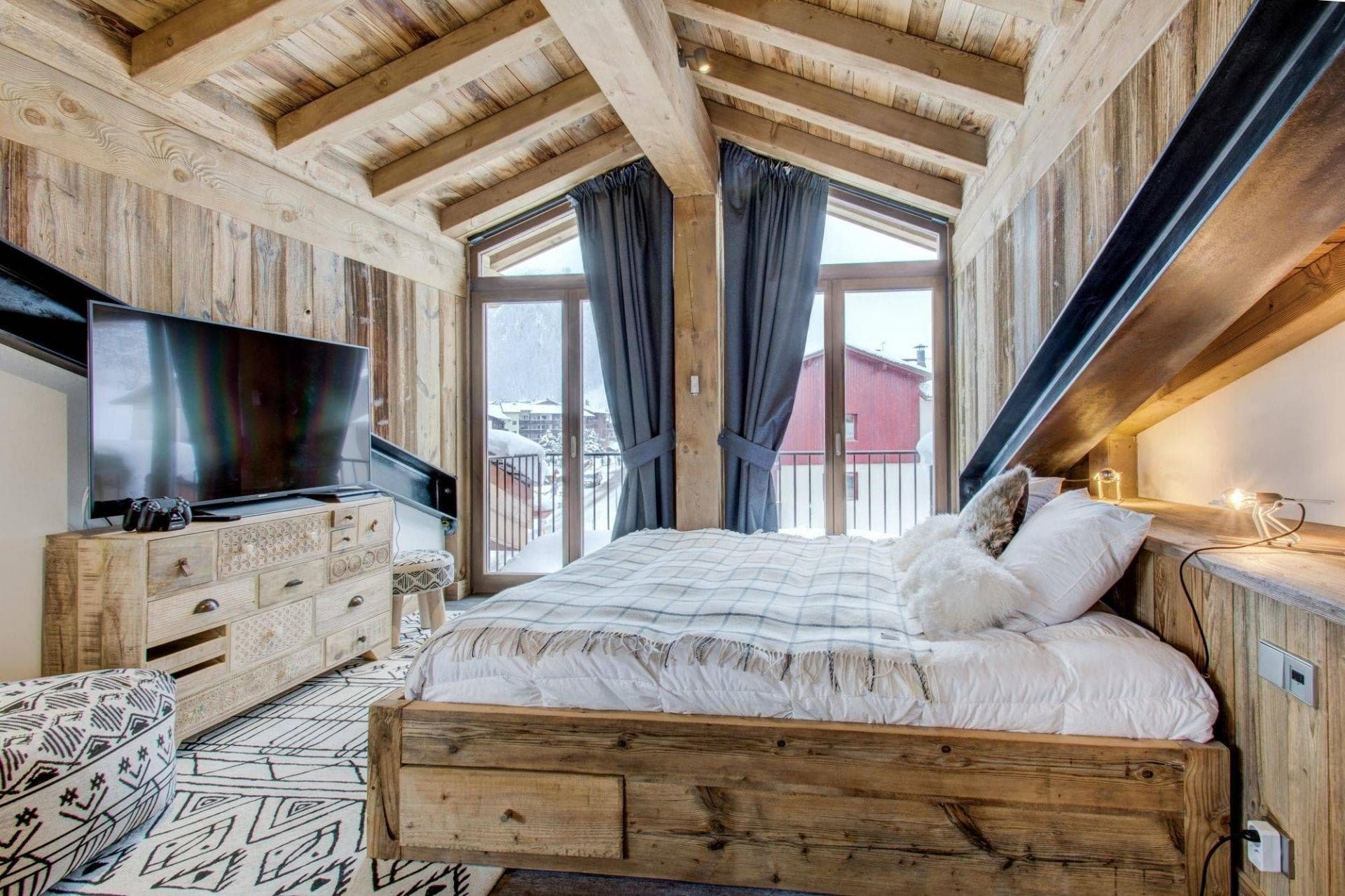 Loft bedroom with exposed beams and mountain-view balcony