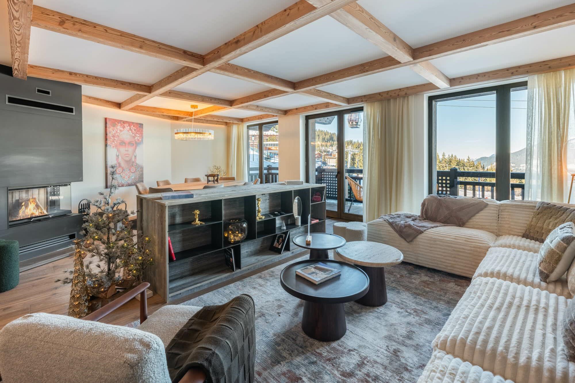Open living area with wood-beam ceilings, fireplace, and balcony access