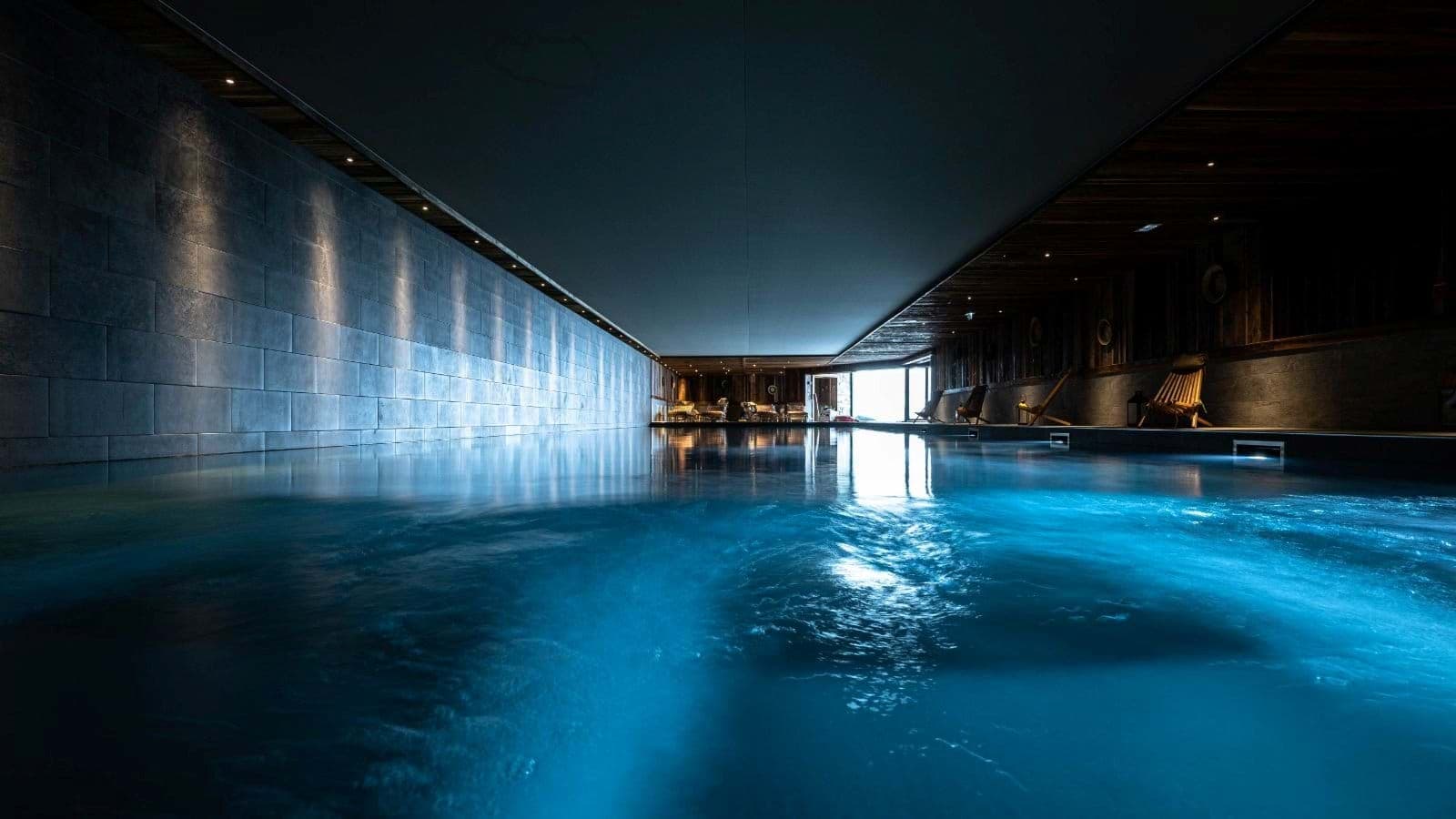 Indoor lap pool with integrated lighting and poolside lounge seating
