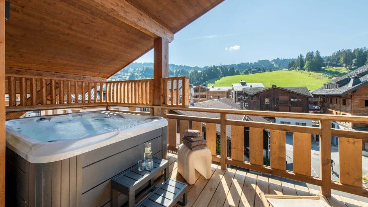 Covered balcony featuring hot tub and alpine slope views