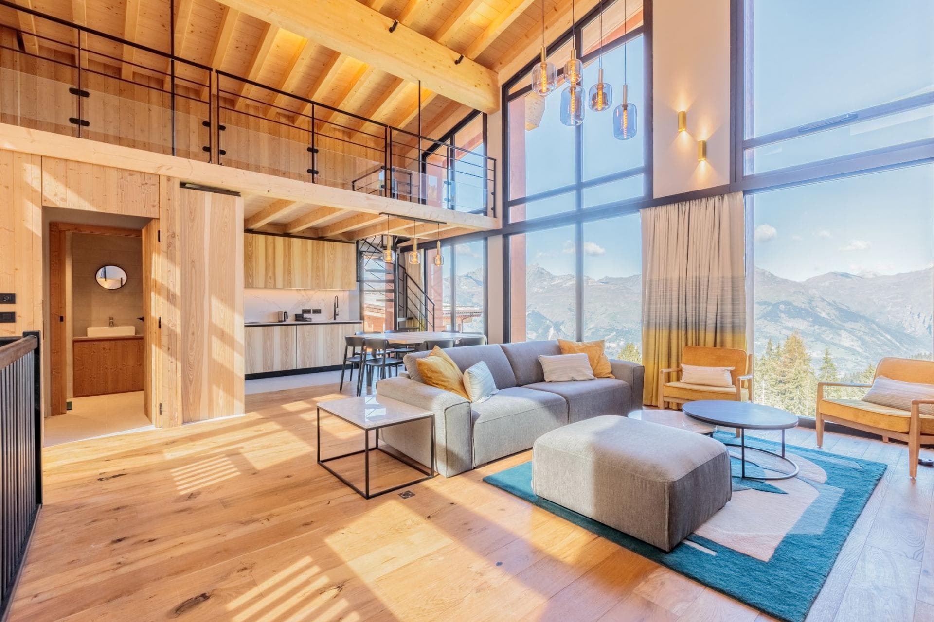 Open-plan living area with floor-to-ceiling mountain views and mezzanine loft