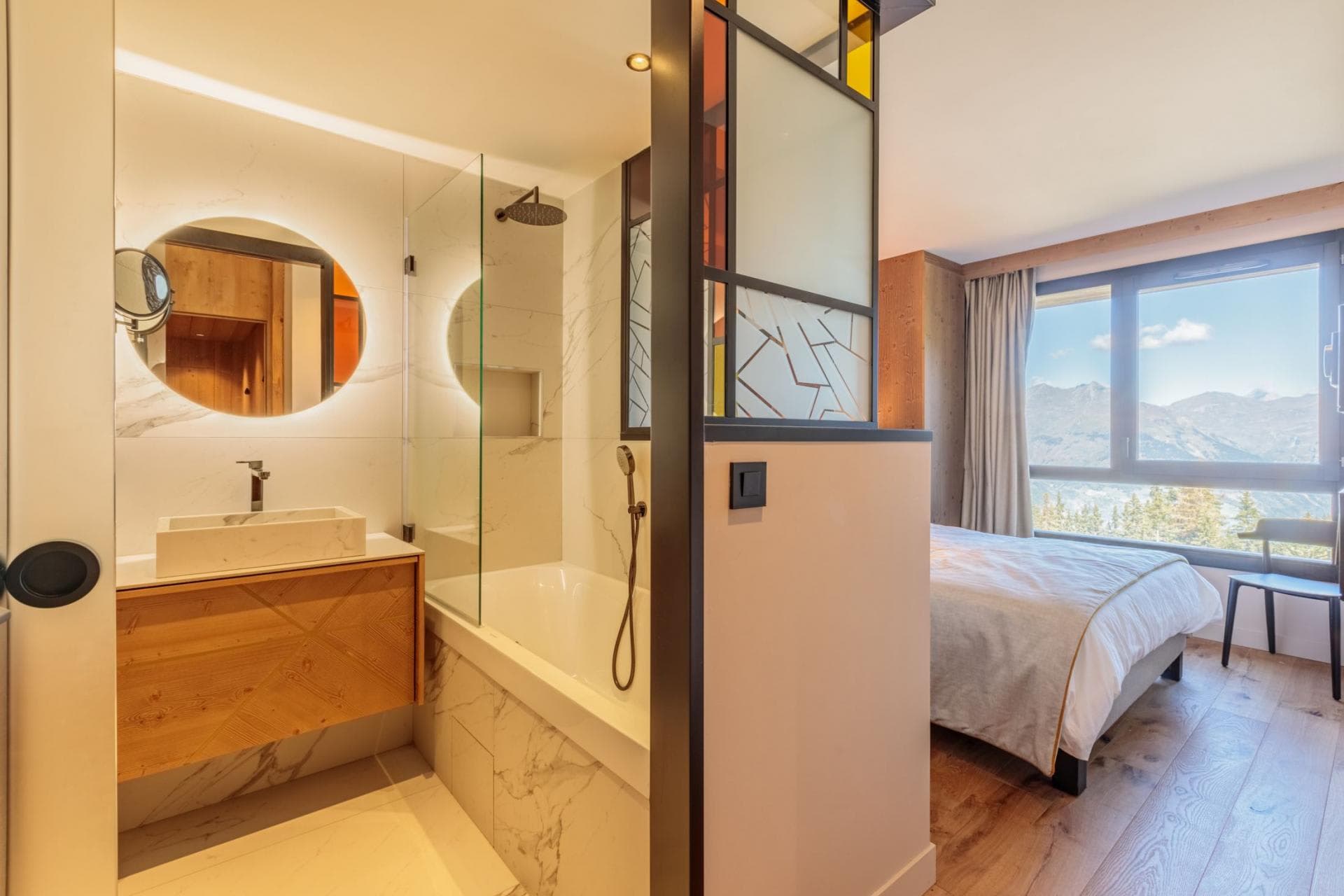 Ensuite bathroom with rainfall shower and soaking tub; mountain views from bed