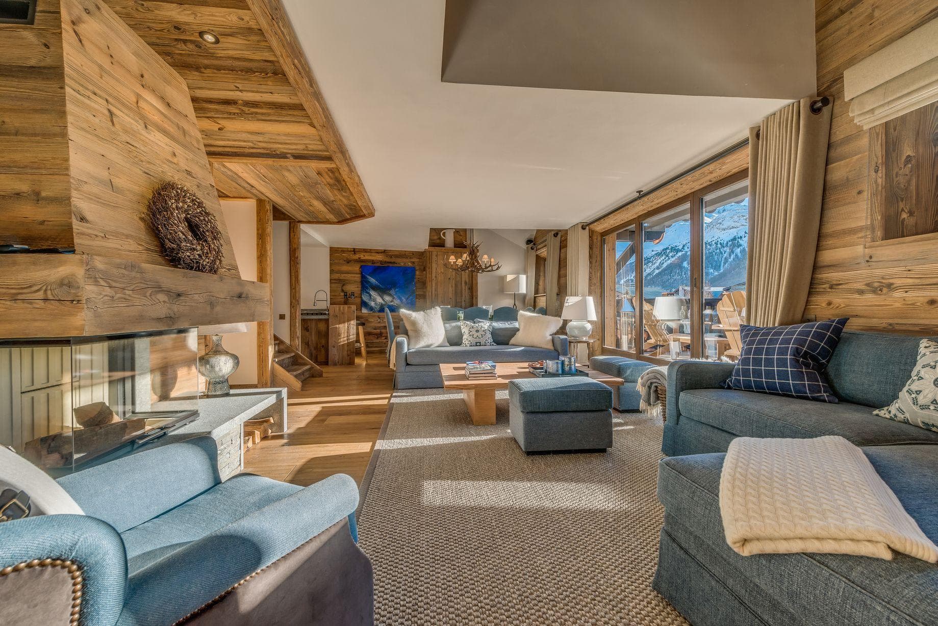 Living room with wood fireplace and floor-to-ceiling mountain views