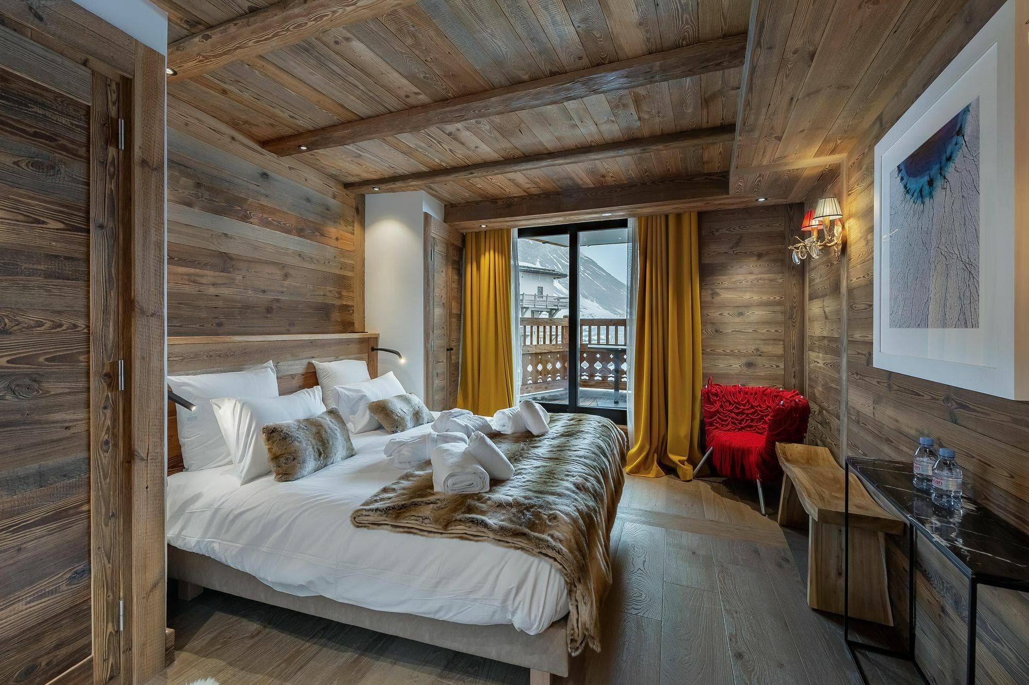 Wood-paneled bedroom with king bed and balcony access to mountain views
