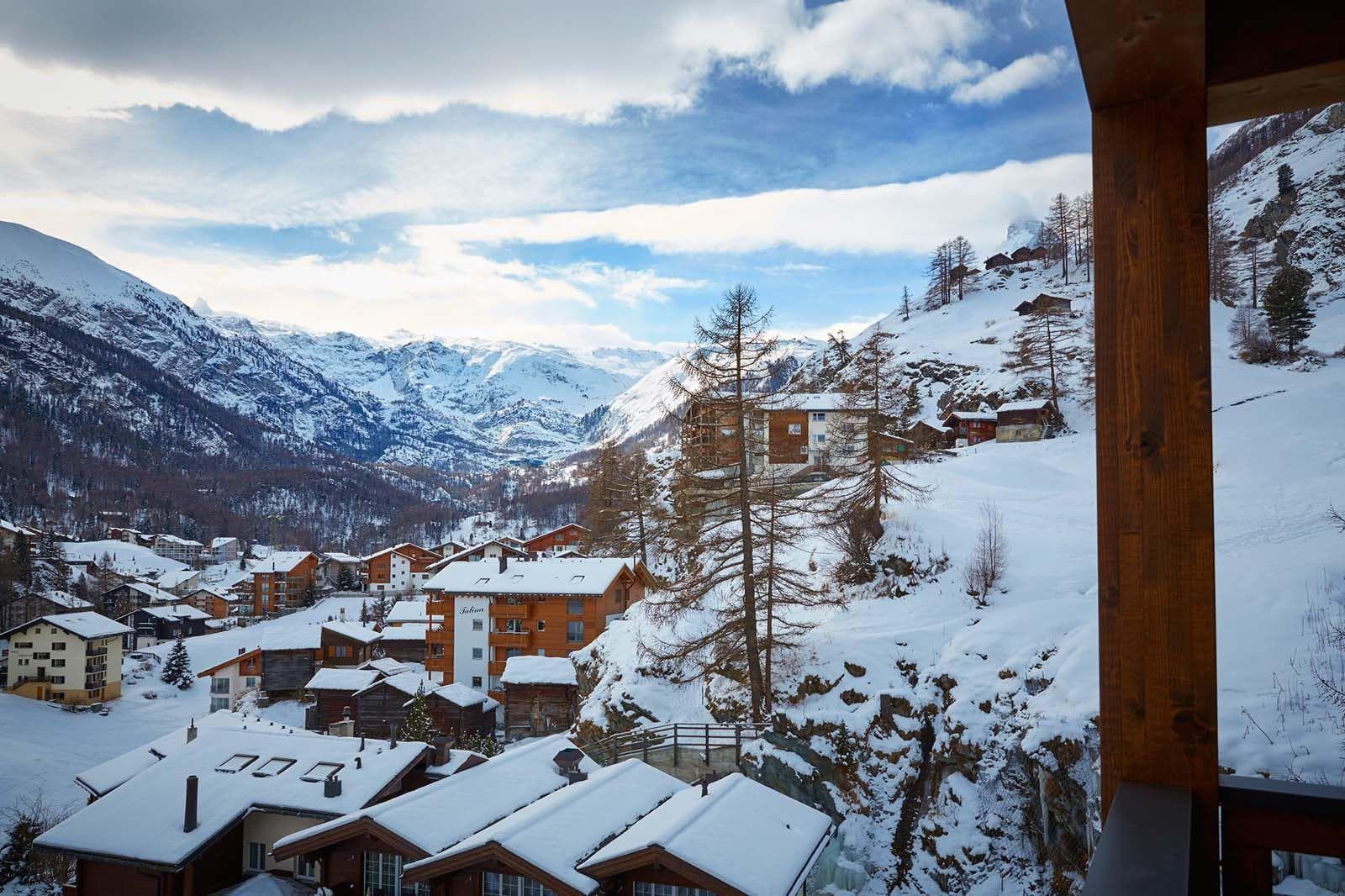 Elevated balcony view overlooking snow-covered village and mountain peaks
