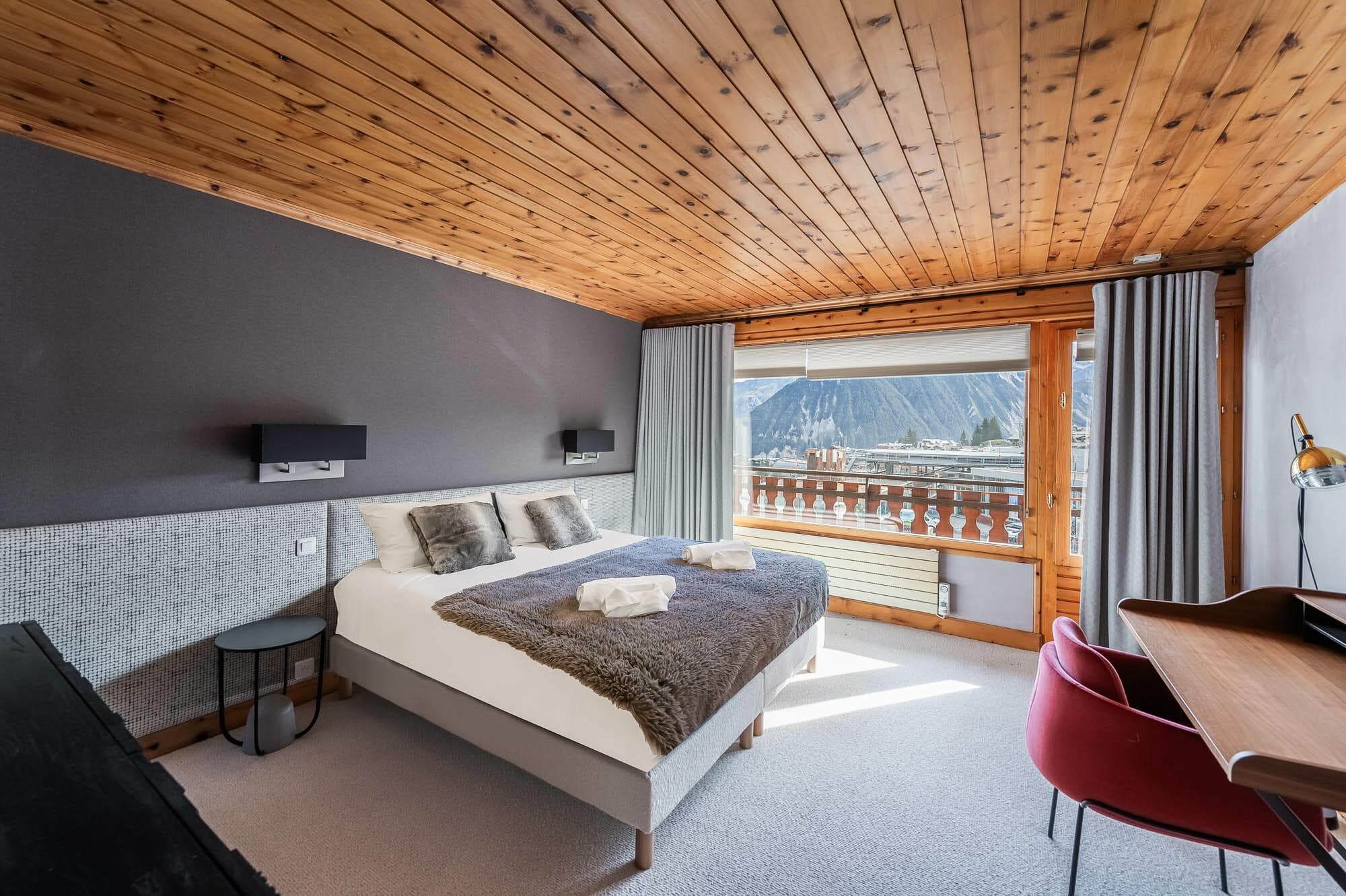 Primary bedroom with king bed, desk, and alpine mountain views