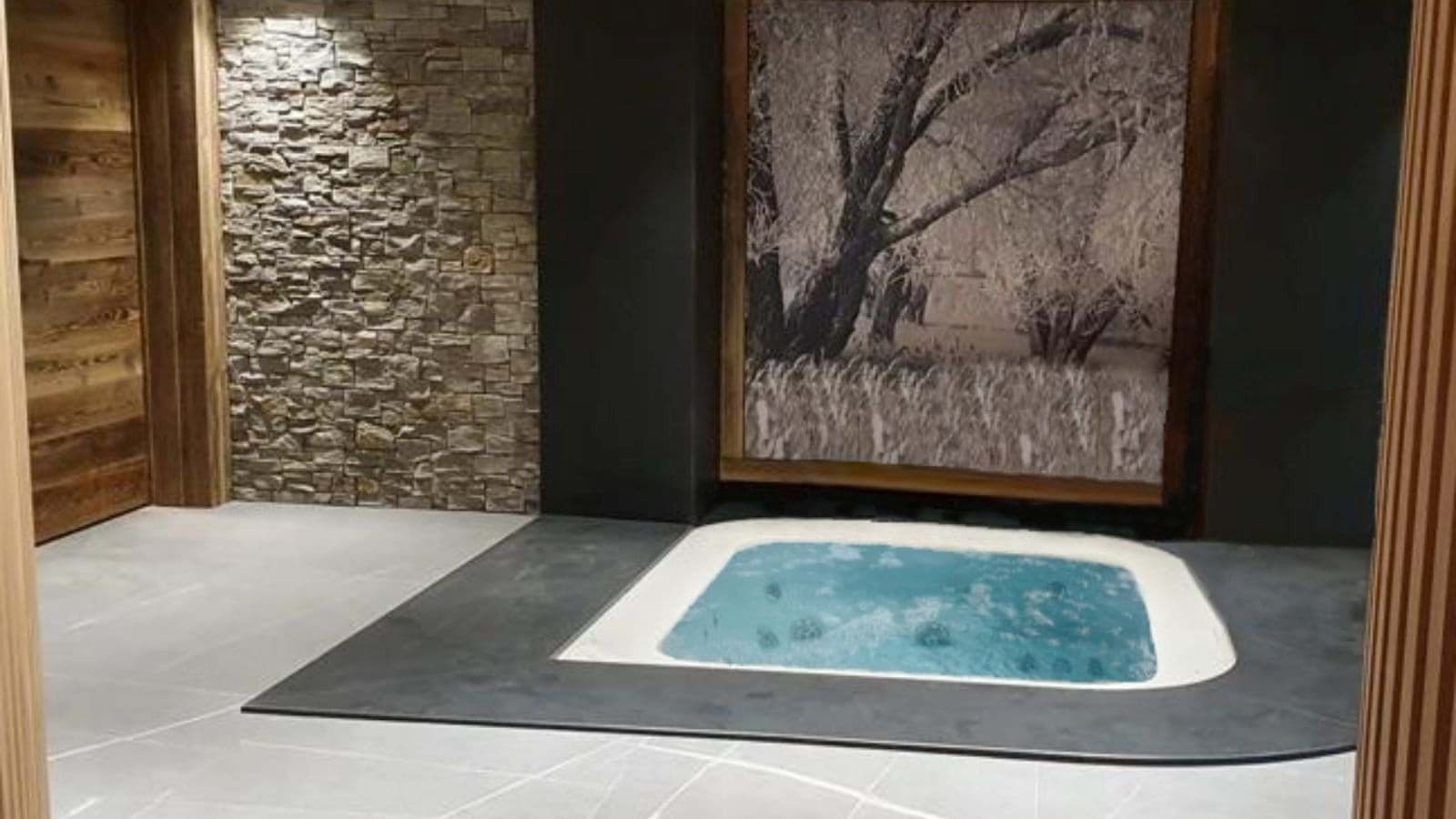 Indoor hot tub with in-floor design and stone feature wall