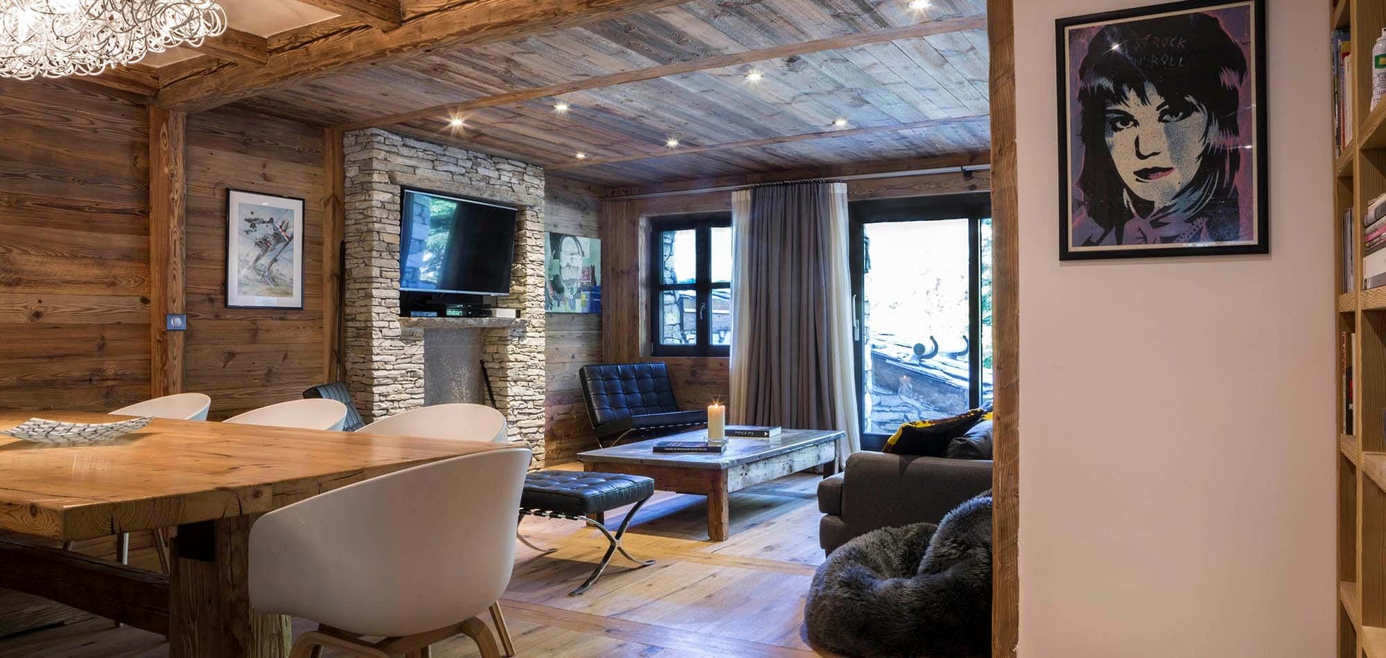 Open living area with wood-paneled walls, stone fireplace, and terrace access
