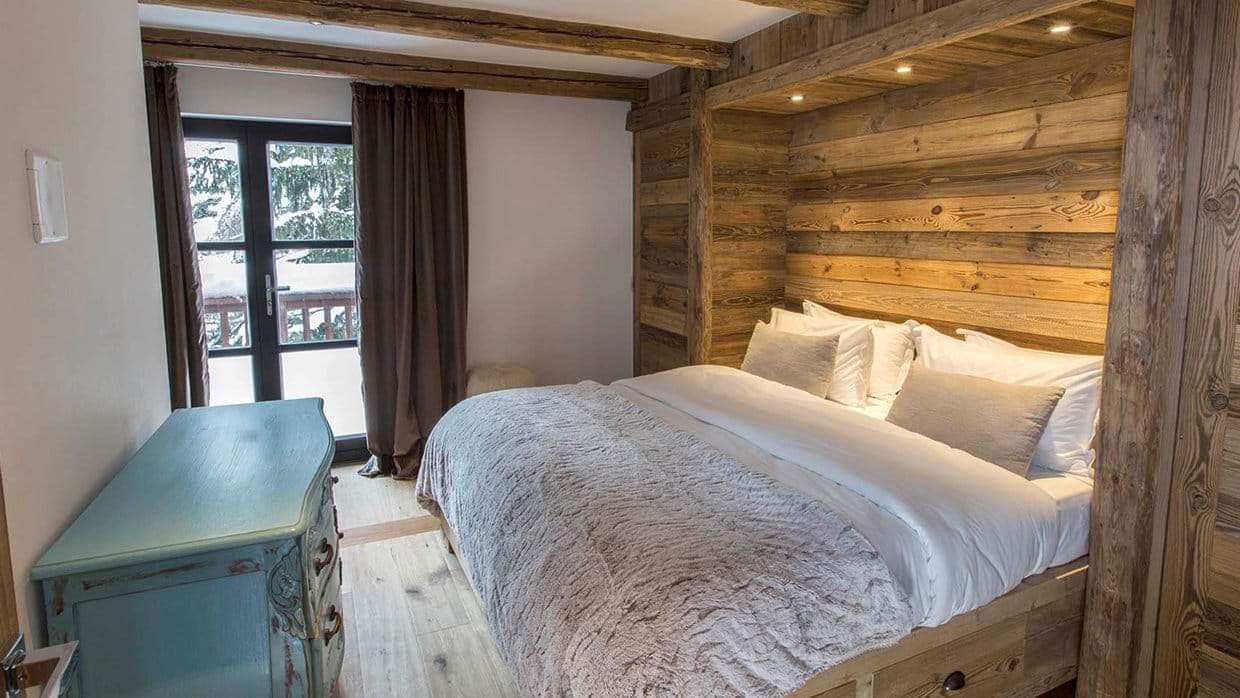 Guest bedroom with king bed, reclaimed wood walls, and balcony access
