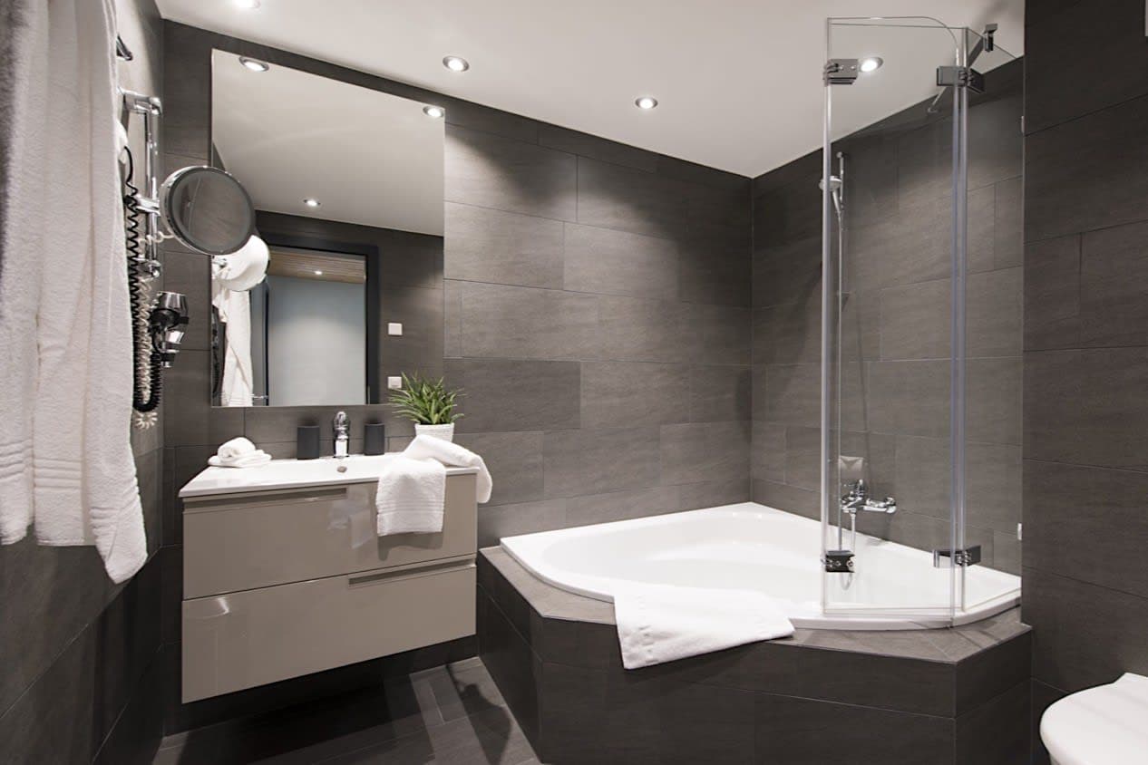 Bathroom with corner soaking tub, rainfall shower, and wall-mounted hairdryer