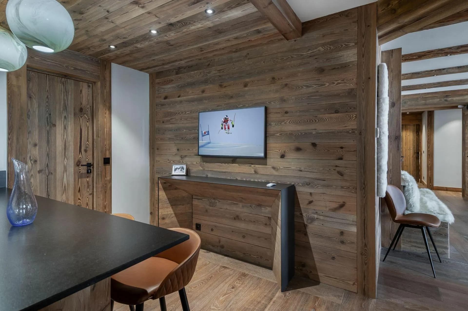 Kitchen breakfast bar seating with wall-mounted TV and reclaimed wood paneling