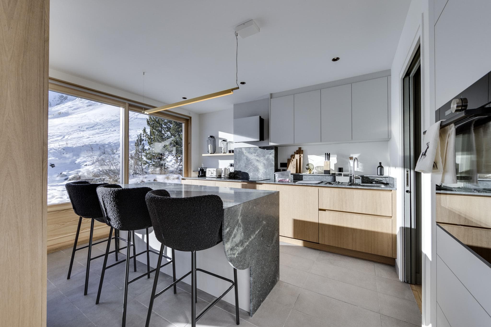 Kitchen with marble waterfall island seating 3 and snowy mountain views