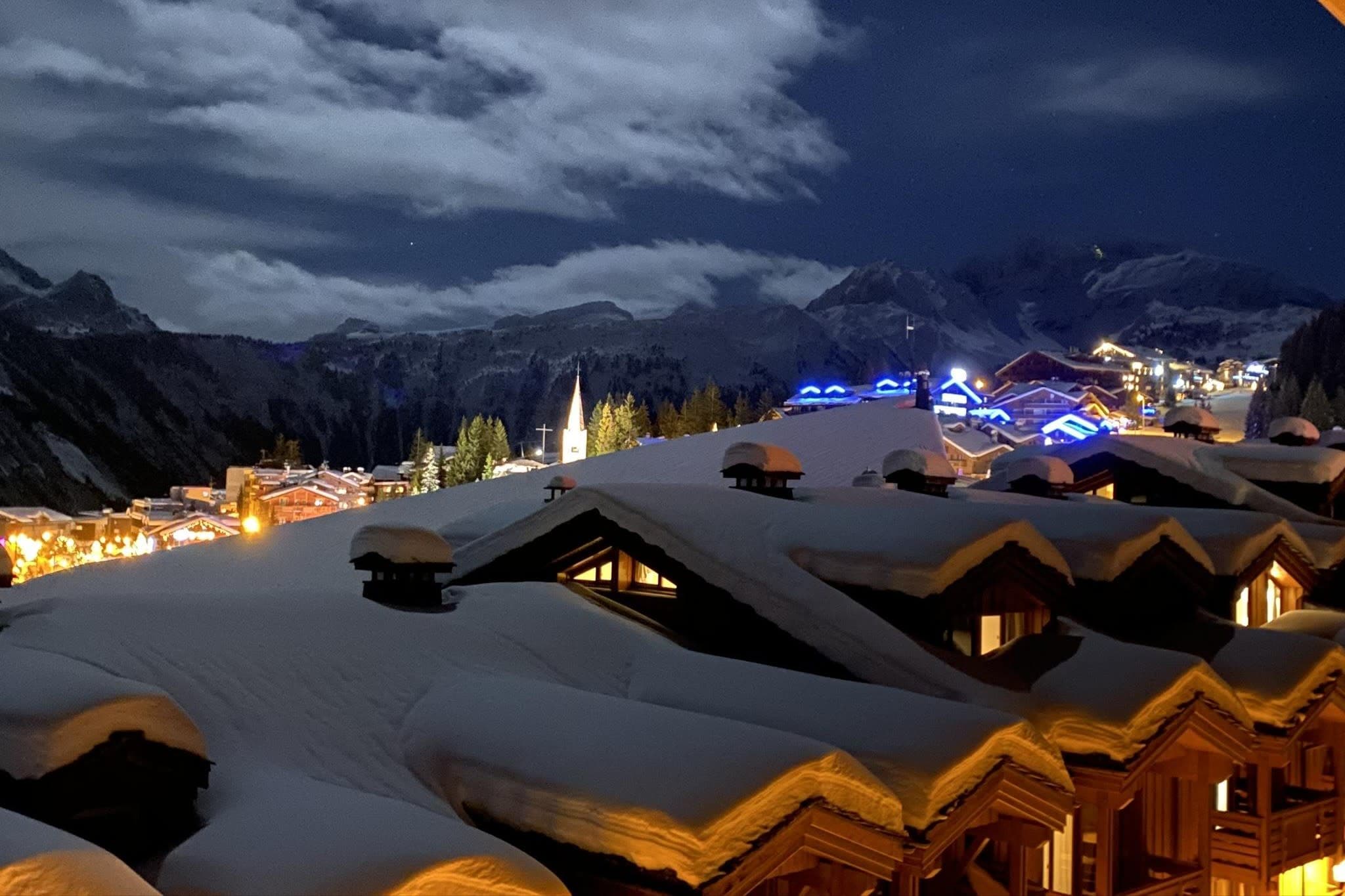 Balcony view of village lights and snow-capped peaks at night
