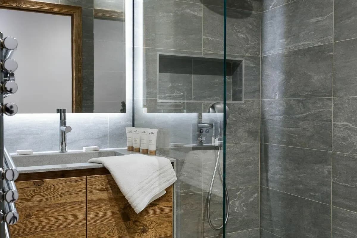 Bathroom featuring walk-in rainfall shower with recessed storage and heated towel rack